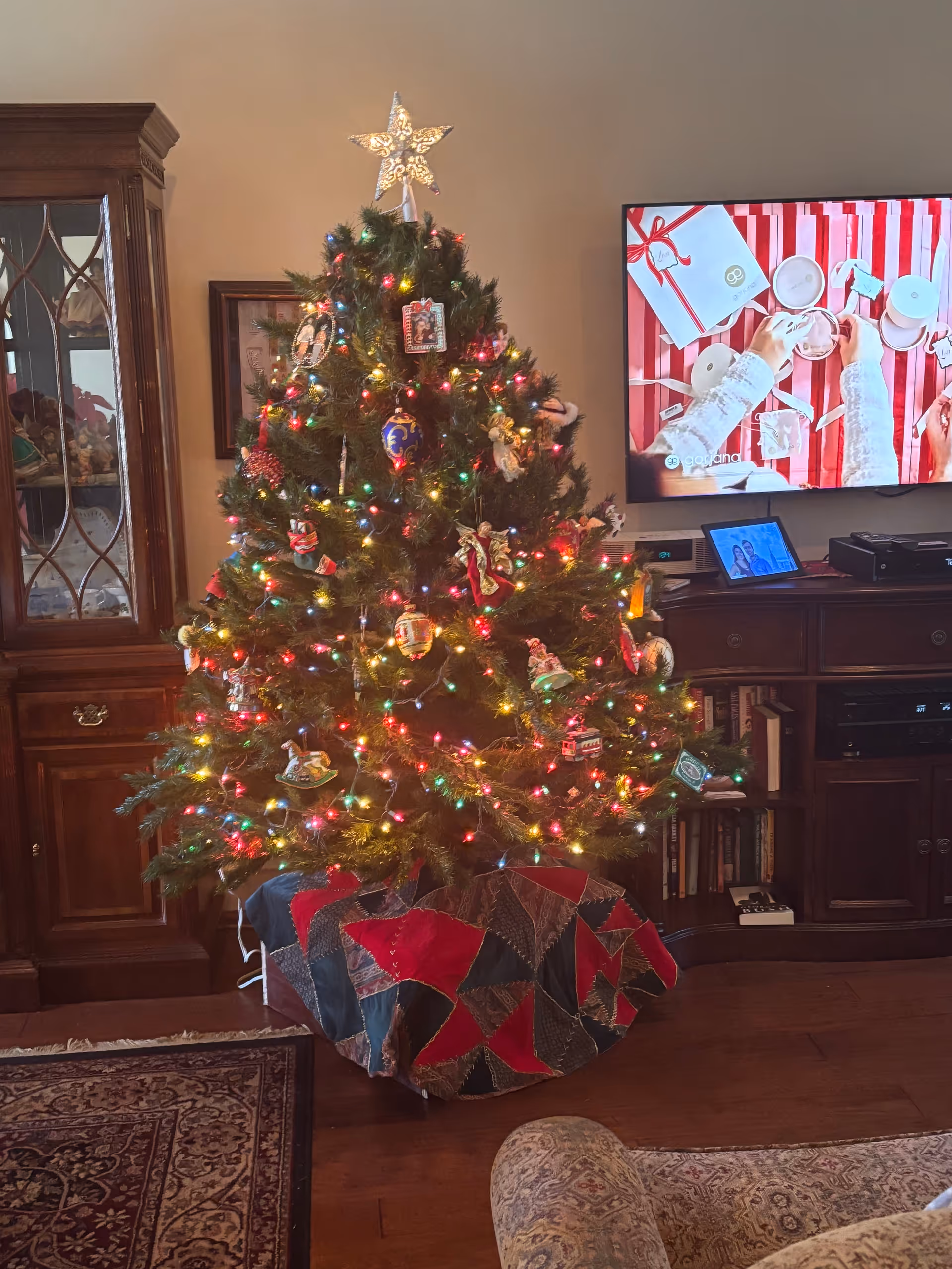 A decorated Christmas tree with colorful lights stands in a cozy living room.
