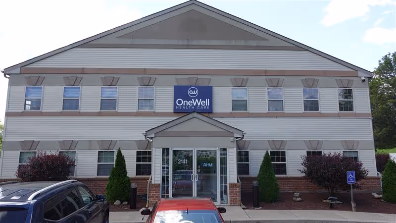 Two-story senior living facility with OneWell Health Care sign and front entrance.