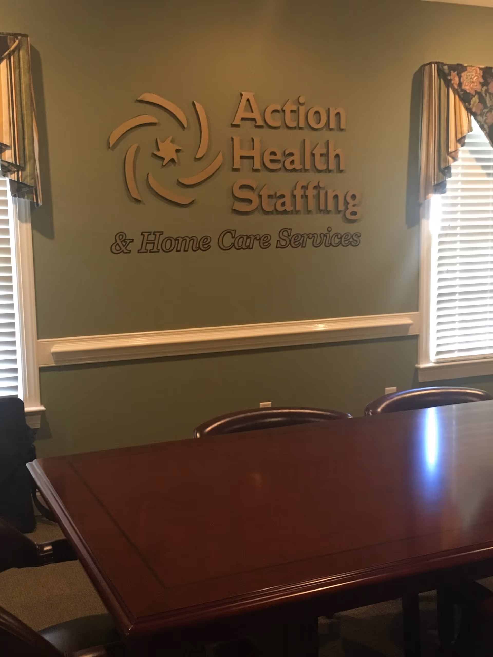 Interior conference room with a wooden table and a sign reading Action Health Staffing.