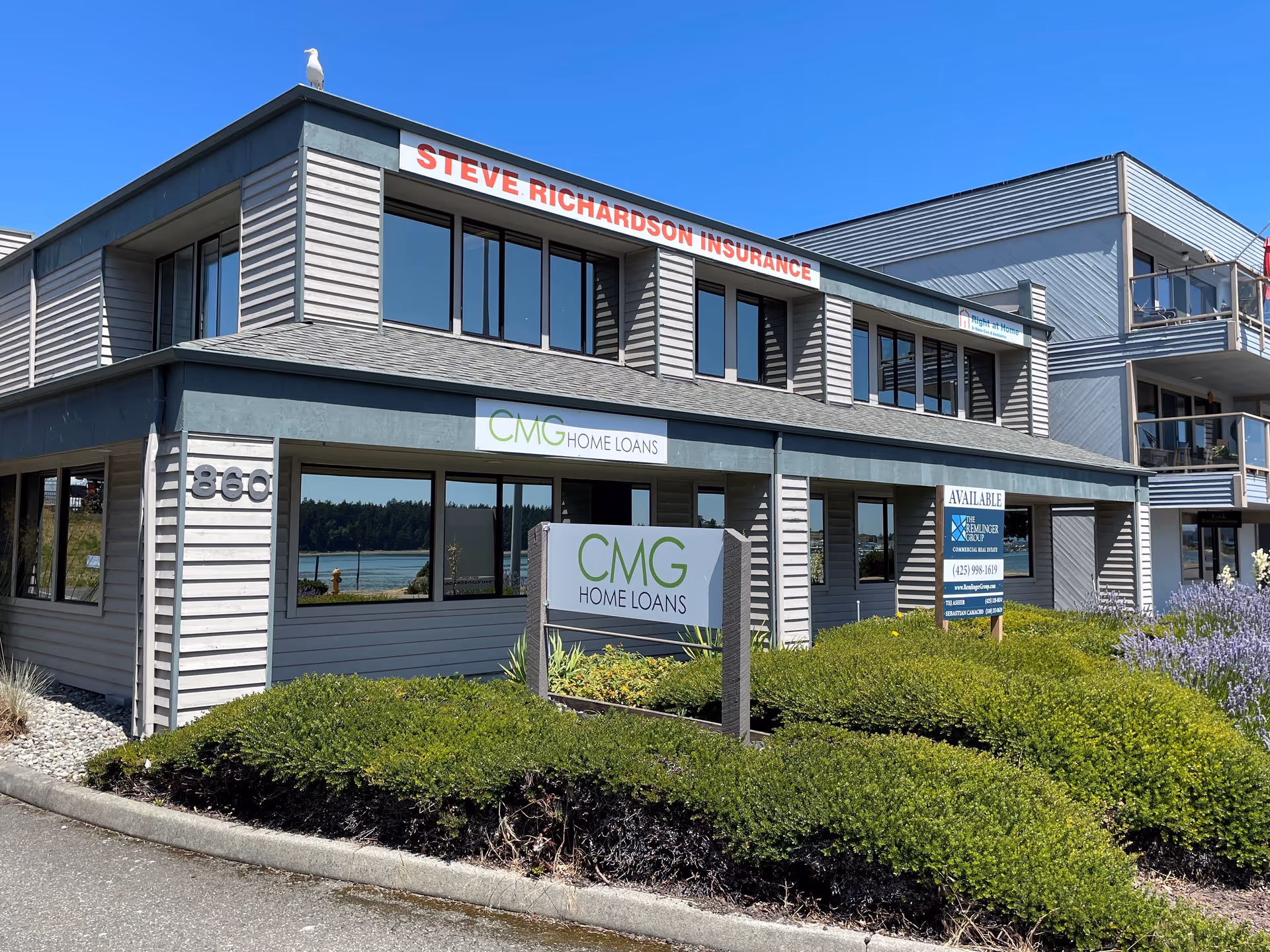 This is a two-story commercial building with street signage and manicured bushes visible.