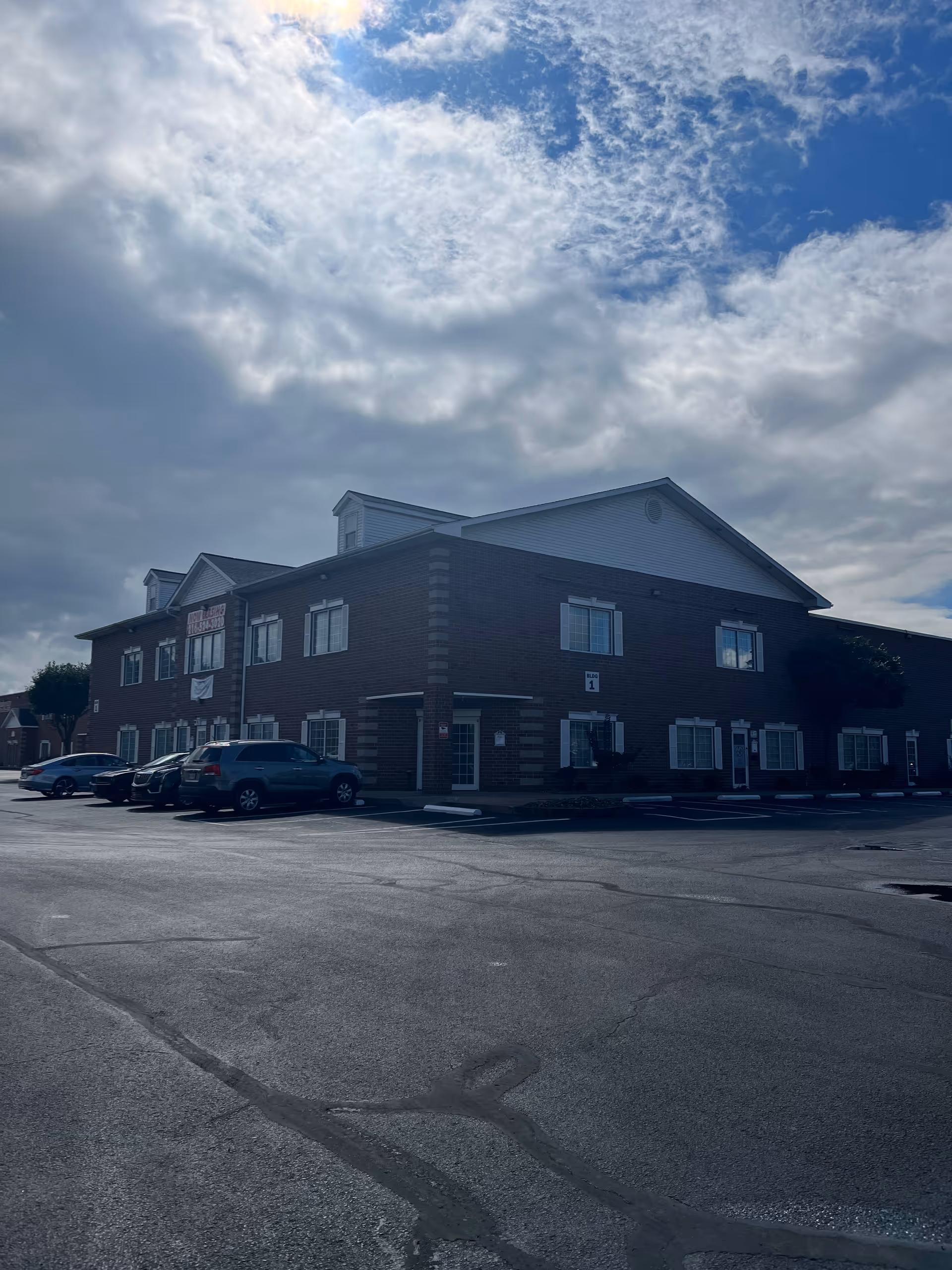 Exterior view of a two-story brick senior living facility with a parking lot.
