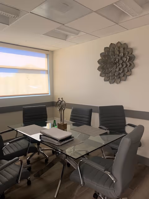 A glass conference table with several gray office chairs in a modern meeting room.