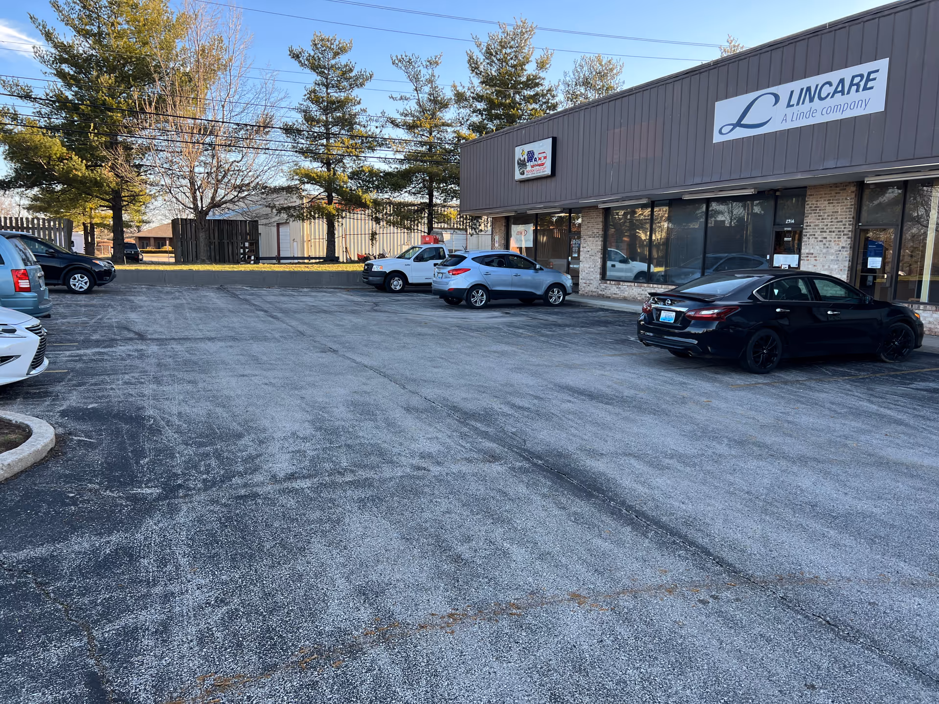 Exterior view of the LINCARE facility with a parking lot and parked cars.
