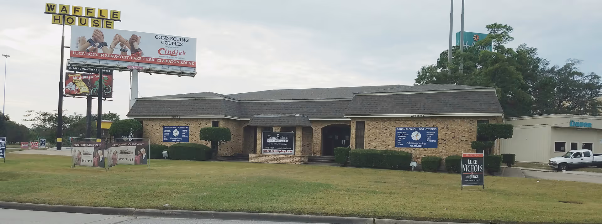 Exterior view of a brick building with Home Instead signage and a nearby Waffle House sign