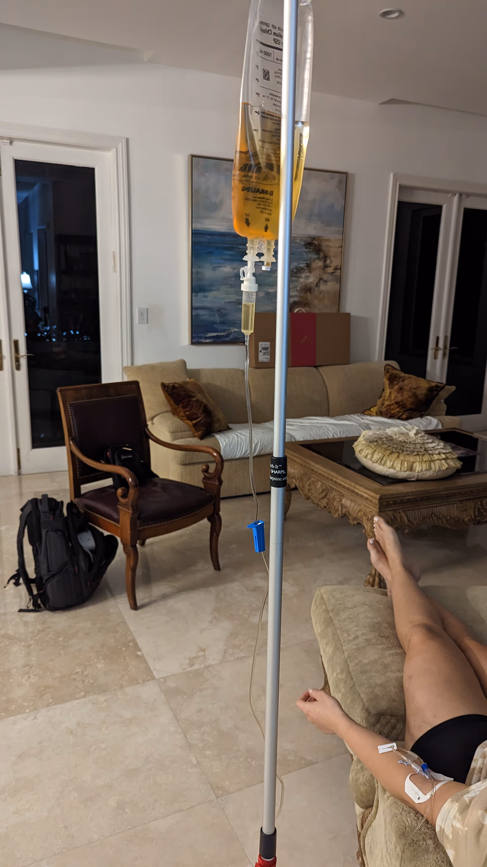 IV infusion stand in a living room with a patient reclining on a sofa.