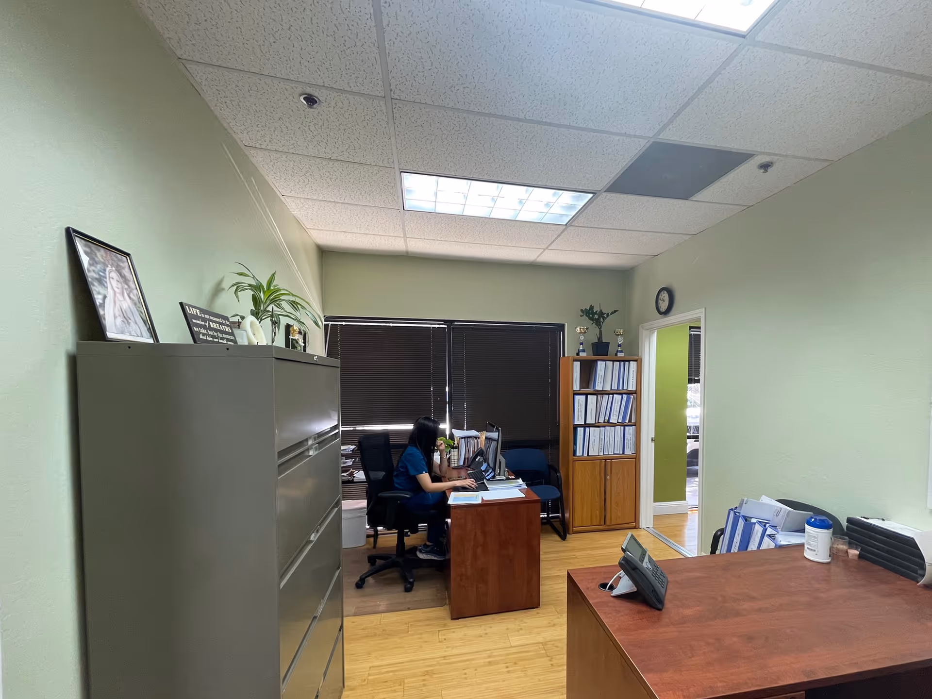 Office inside a senior care facility with a desk, filing cabinet, and a staff member working.
