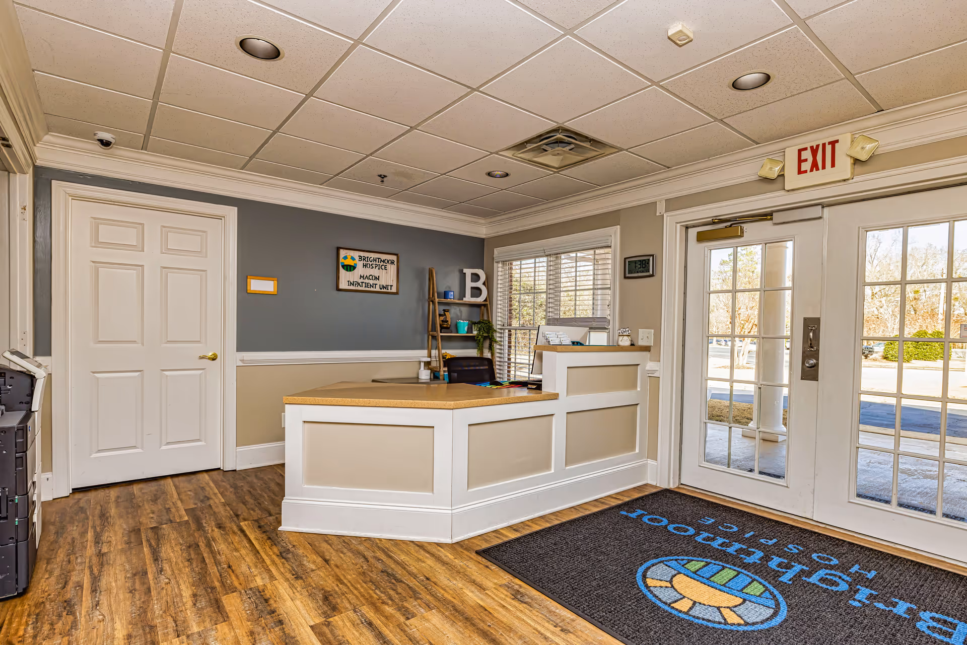 Reception desk in Brightmoor Hospice lobby with exit door and glass windows.