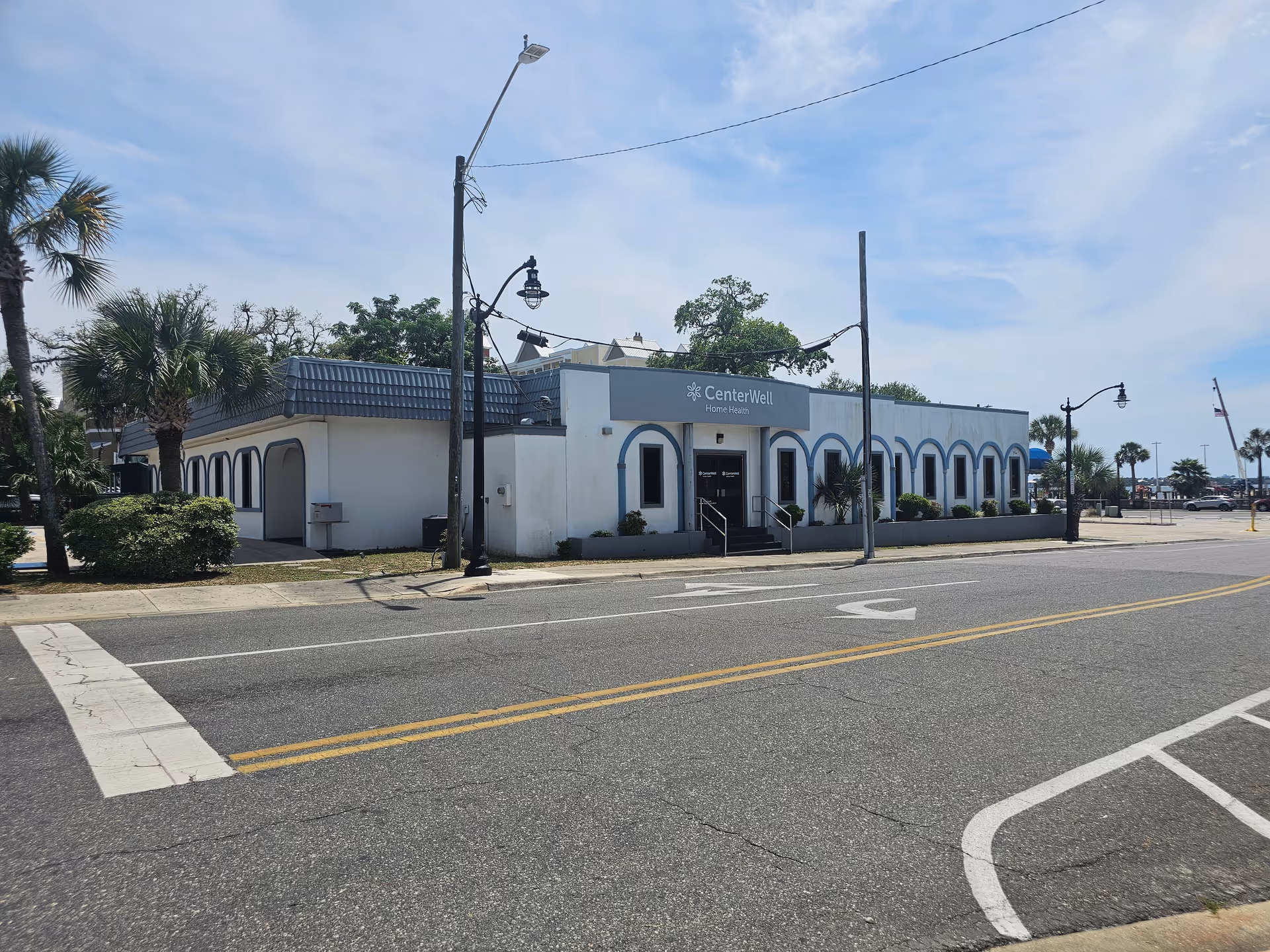 Front view of CenterWell Home Health building along a street with palm trees and parking.