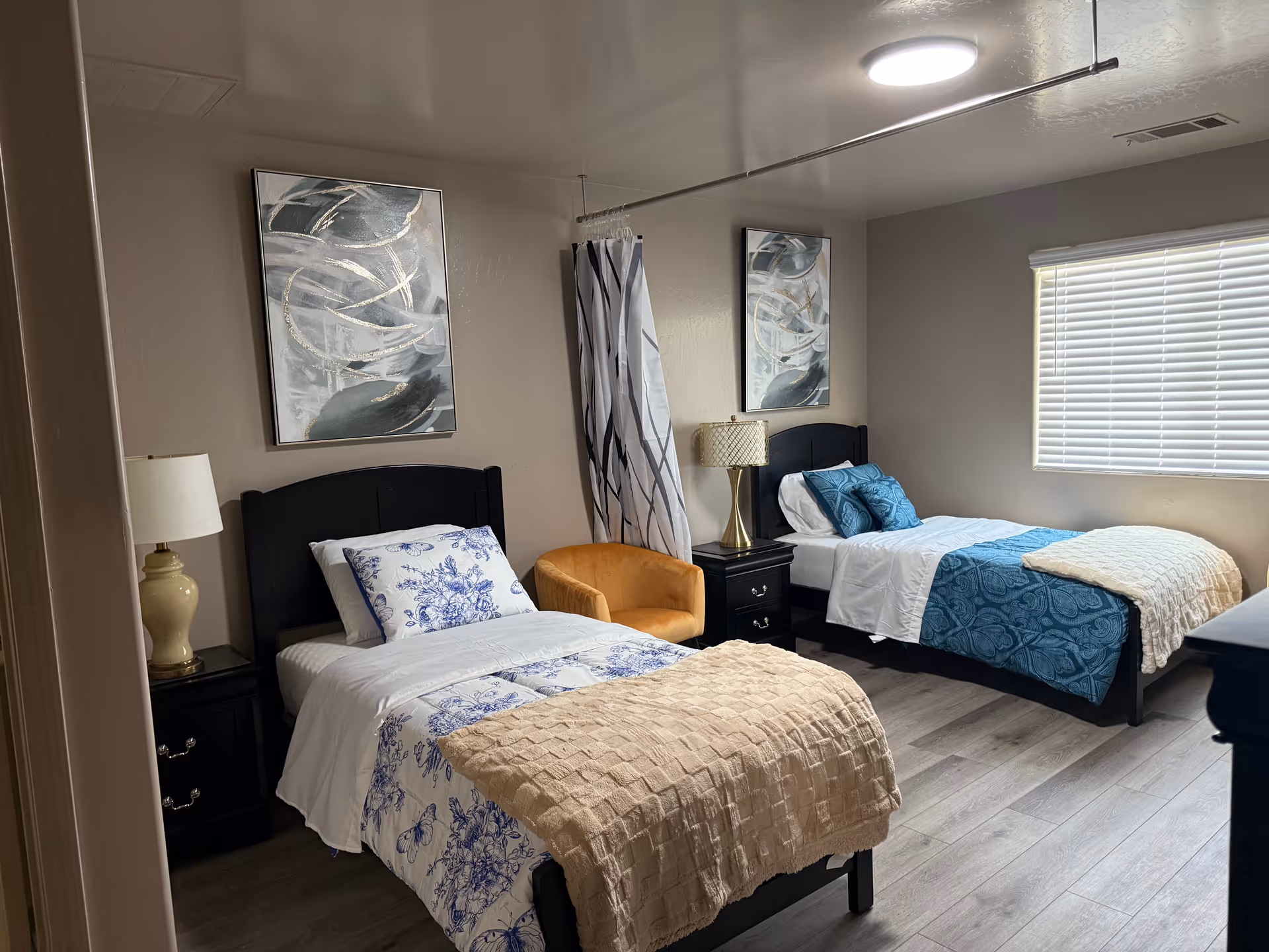 Two twin beds with matching bedding, nightstands, and an orange chair in a shared bedroom.