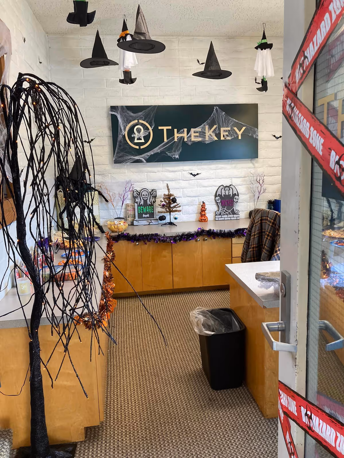 Reception area with Halloween decorations and a TheKey sign on a white brick wall.