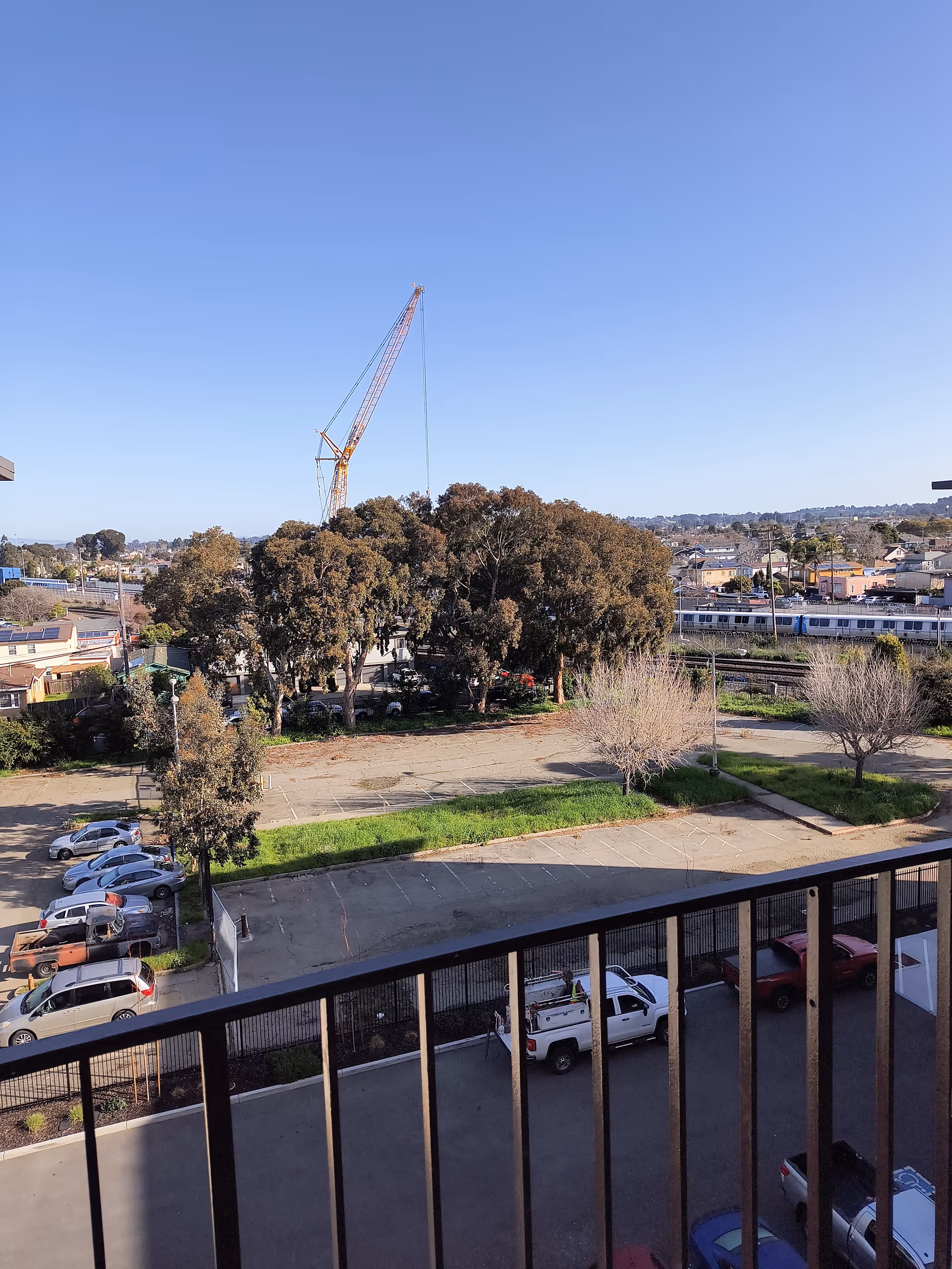 Outdoor view showing a parking lot, trees, and a crane near a building.