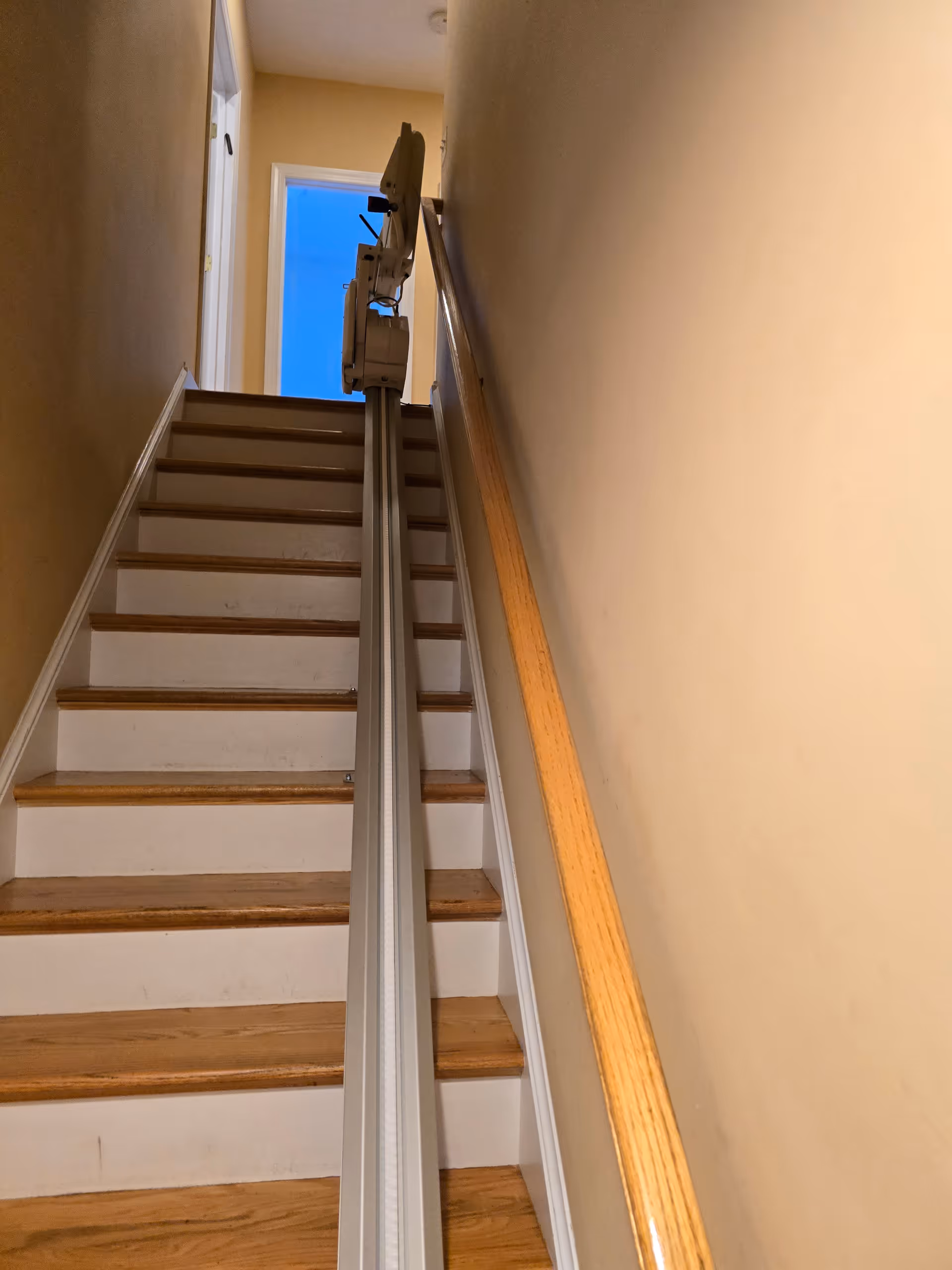 Interior stairwell showing a mounted stairlift along the center rail.