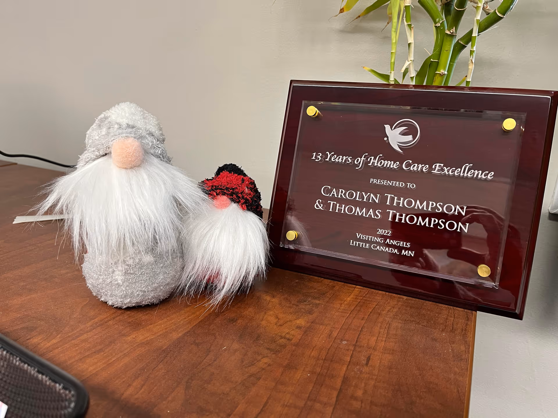 plaque on desk beside two plush gnome decorations in a Visiting Angels office