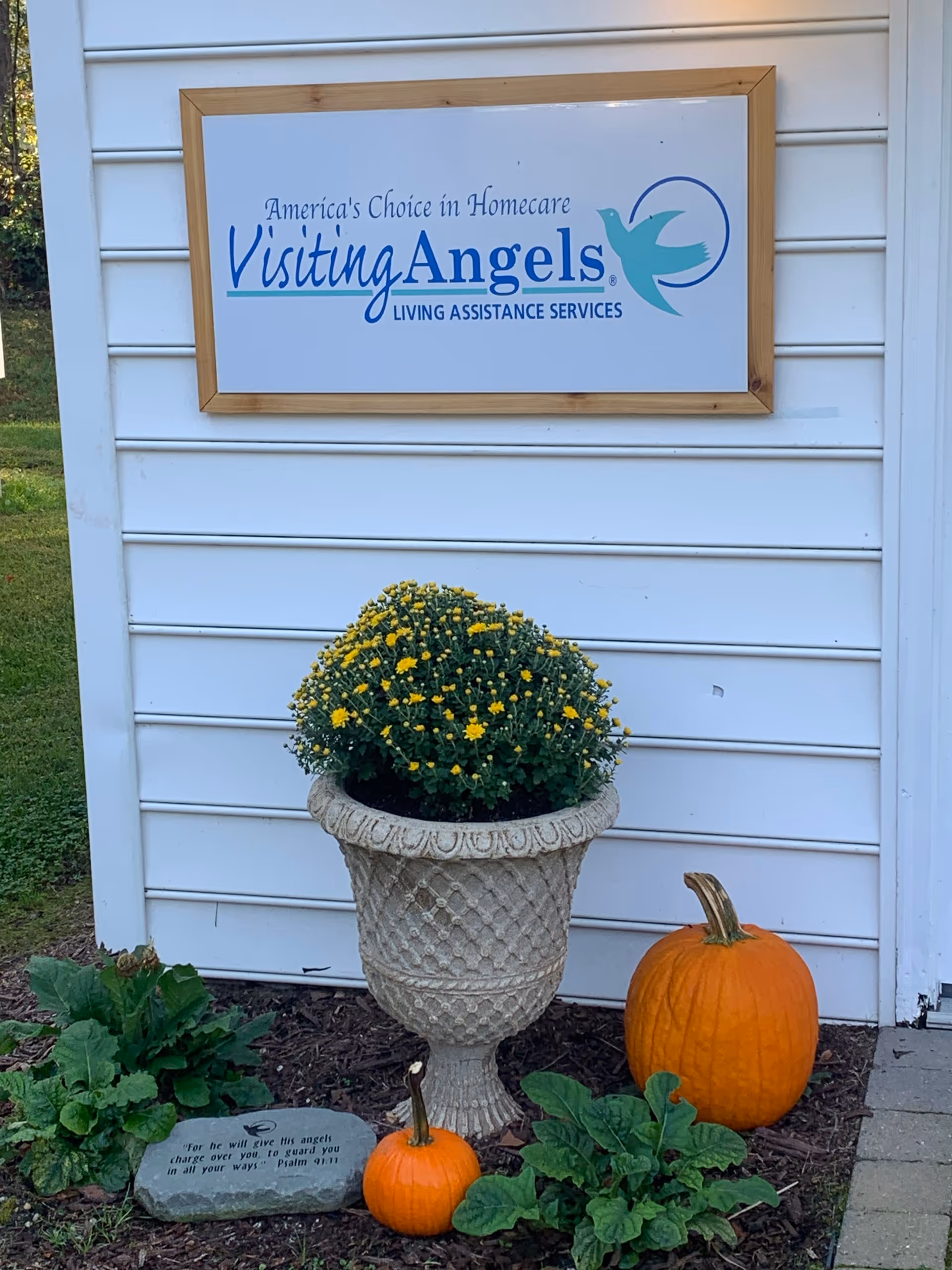 Front exterior wall of Visiting Angels Senior Home Care with sign, pumpkins, and a potted plant.