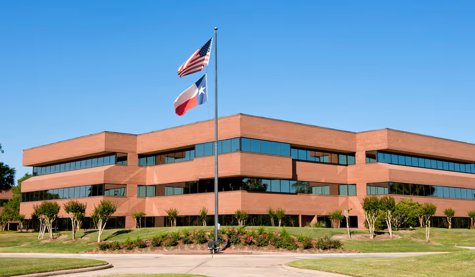 Exterior brick building with flags and landscaped lawn