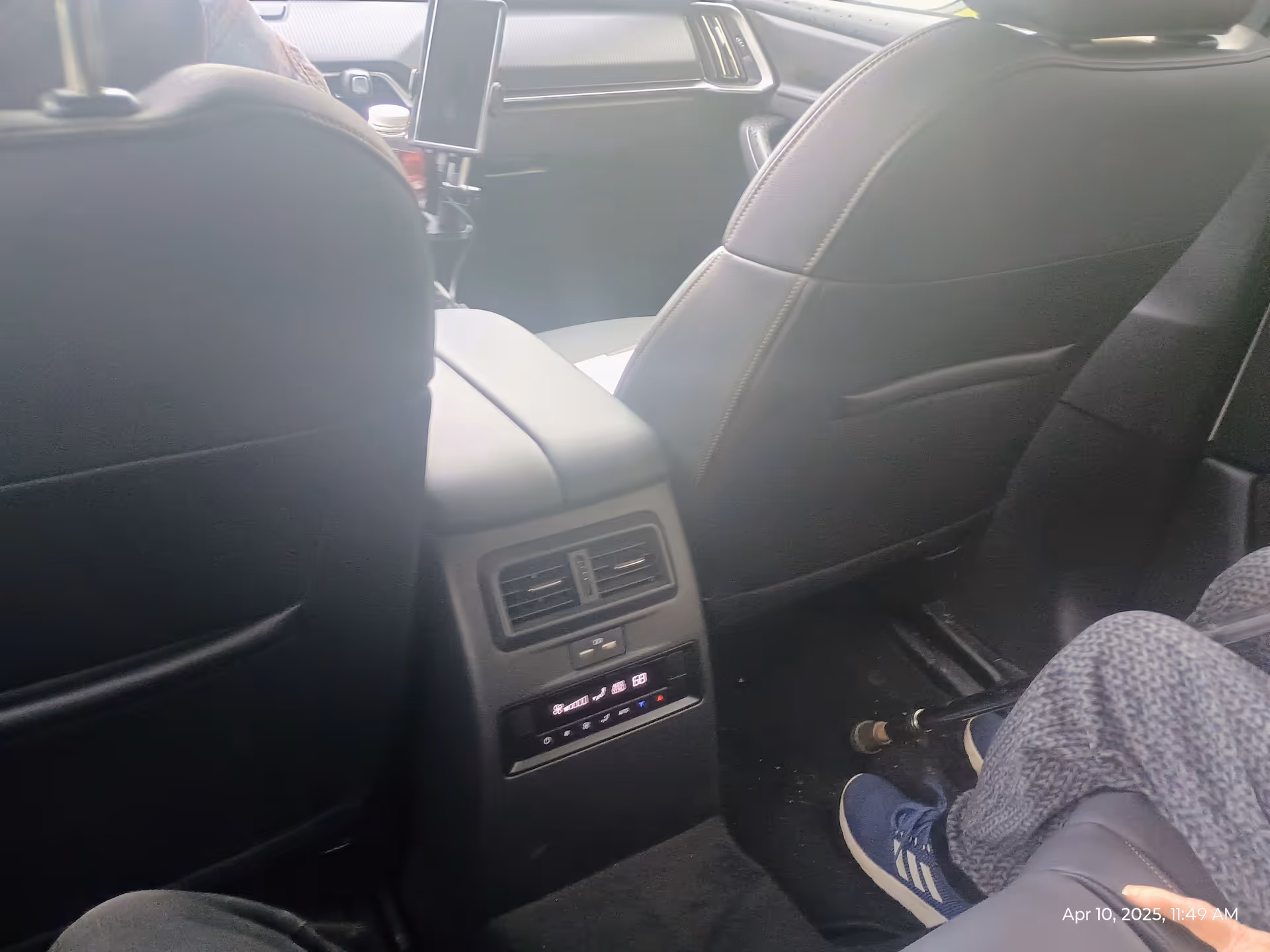 Backseat view of a car with rear vents and a passenger's legs.