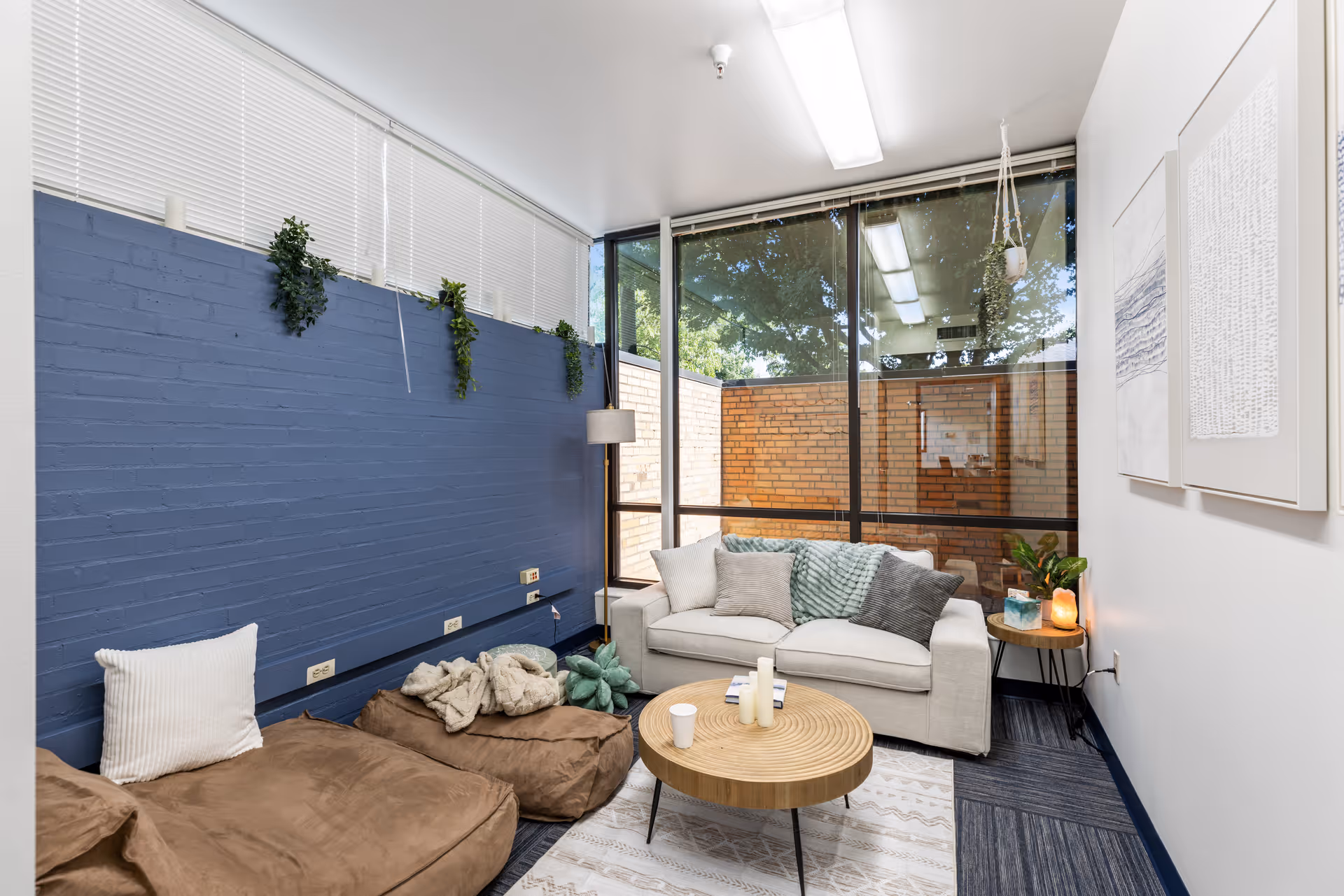 Cozy indoor living lounge with blue brick wall, bean bags, sofa, and large windows.