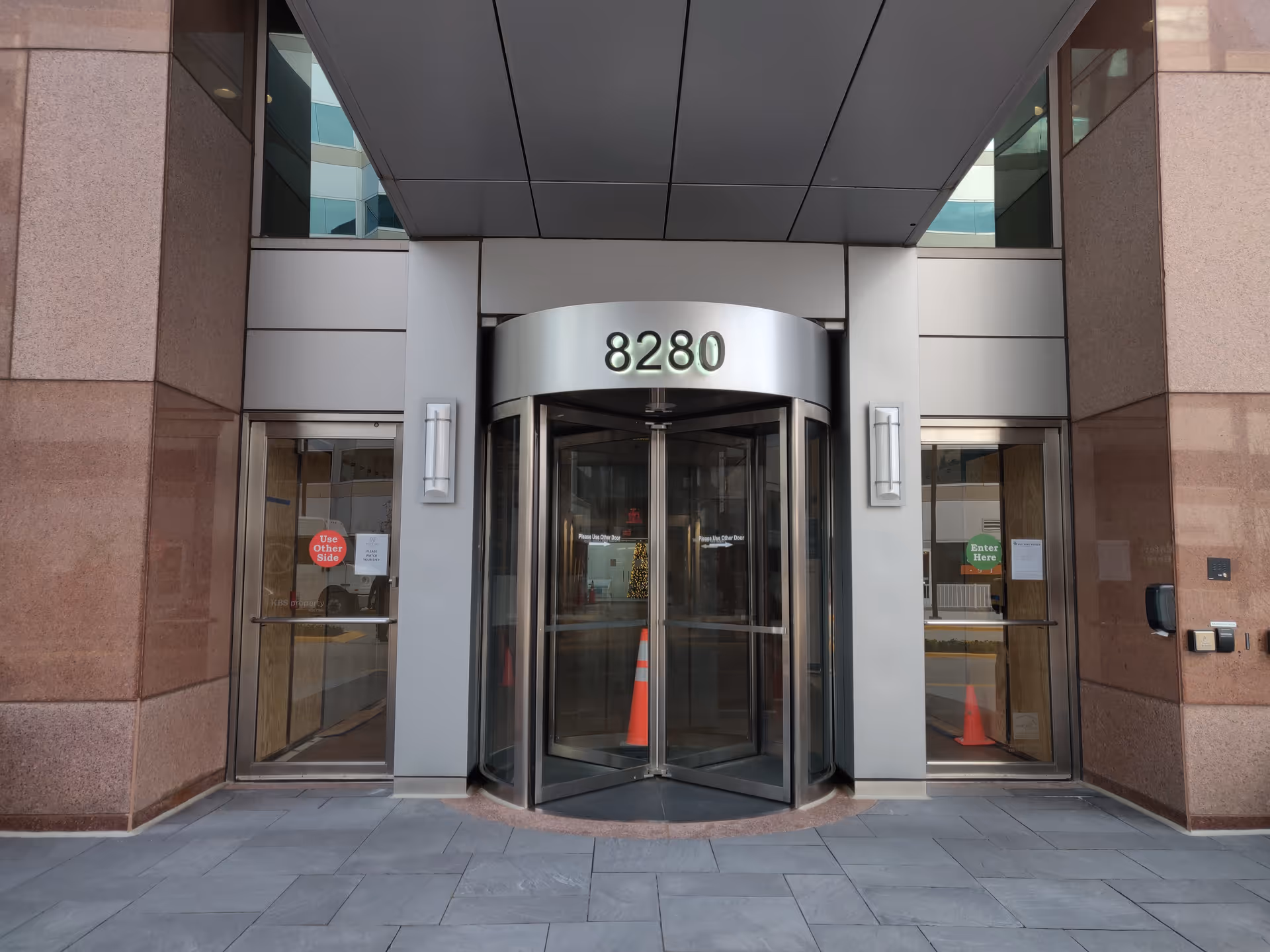 Front entrance of a modern building with revolving doors and the number 8280.