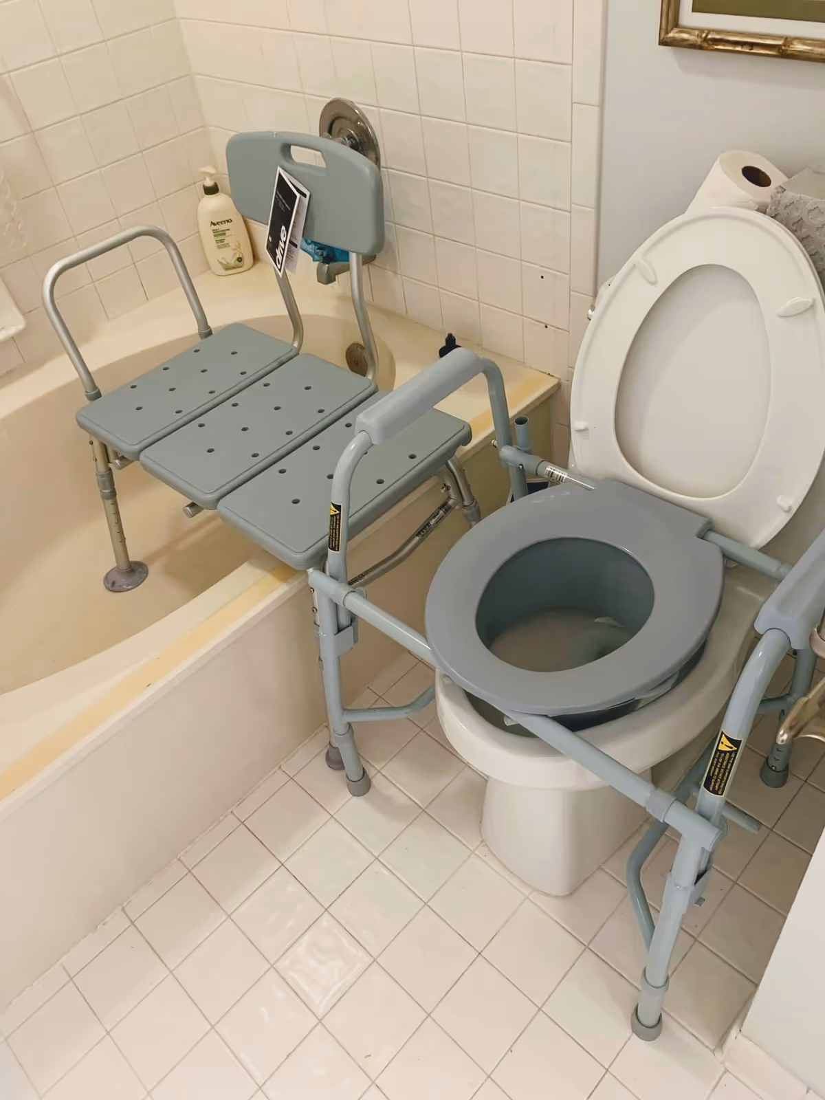 Bathroom with a transfer bench beside a toilet and bathtub.