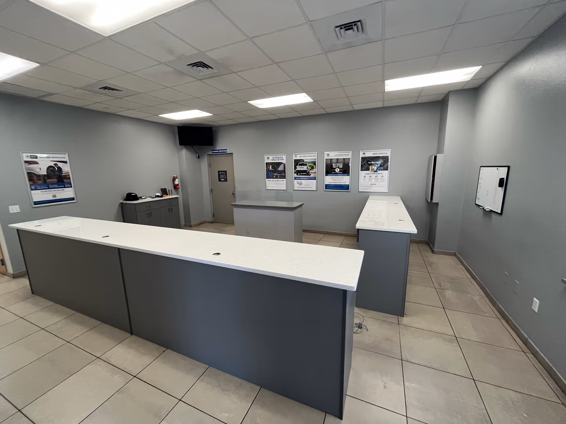 A modern reception desk and counters in a gray interior lobby.