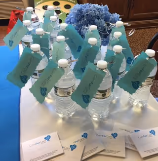 Bottled water with teal tags arranged on a table indoors at ComForCare.