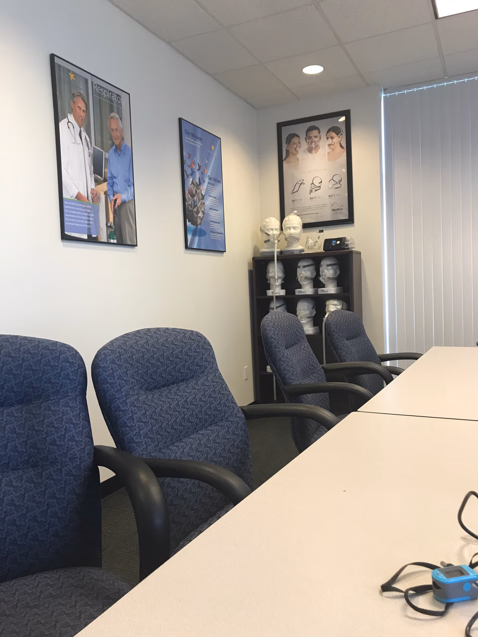 A conference room with blue chairs around a long table and posters on the walls.