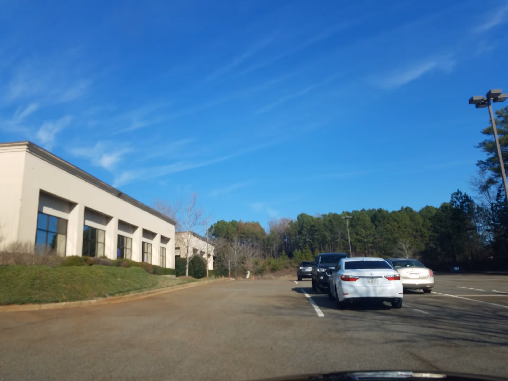 Exterior view of Adoration Home Health building with a parking lot and blue sky.