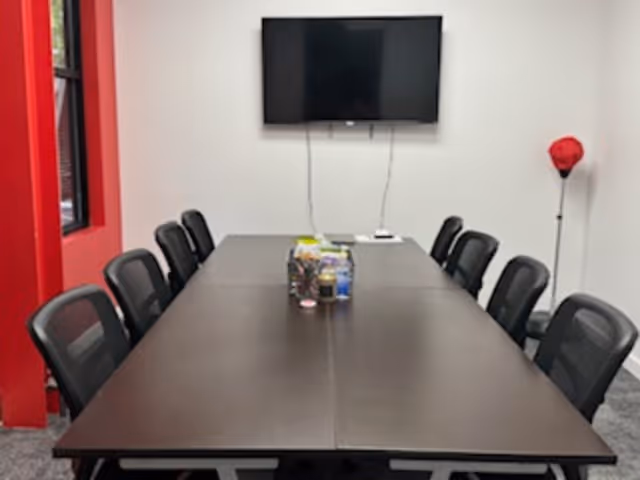 Long meeting table with chairs in BAYADA Assistive Care conference room; wall-mounted TV.