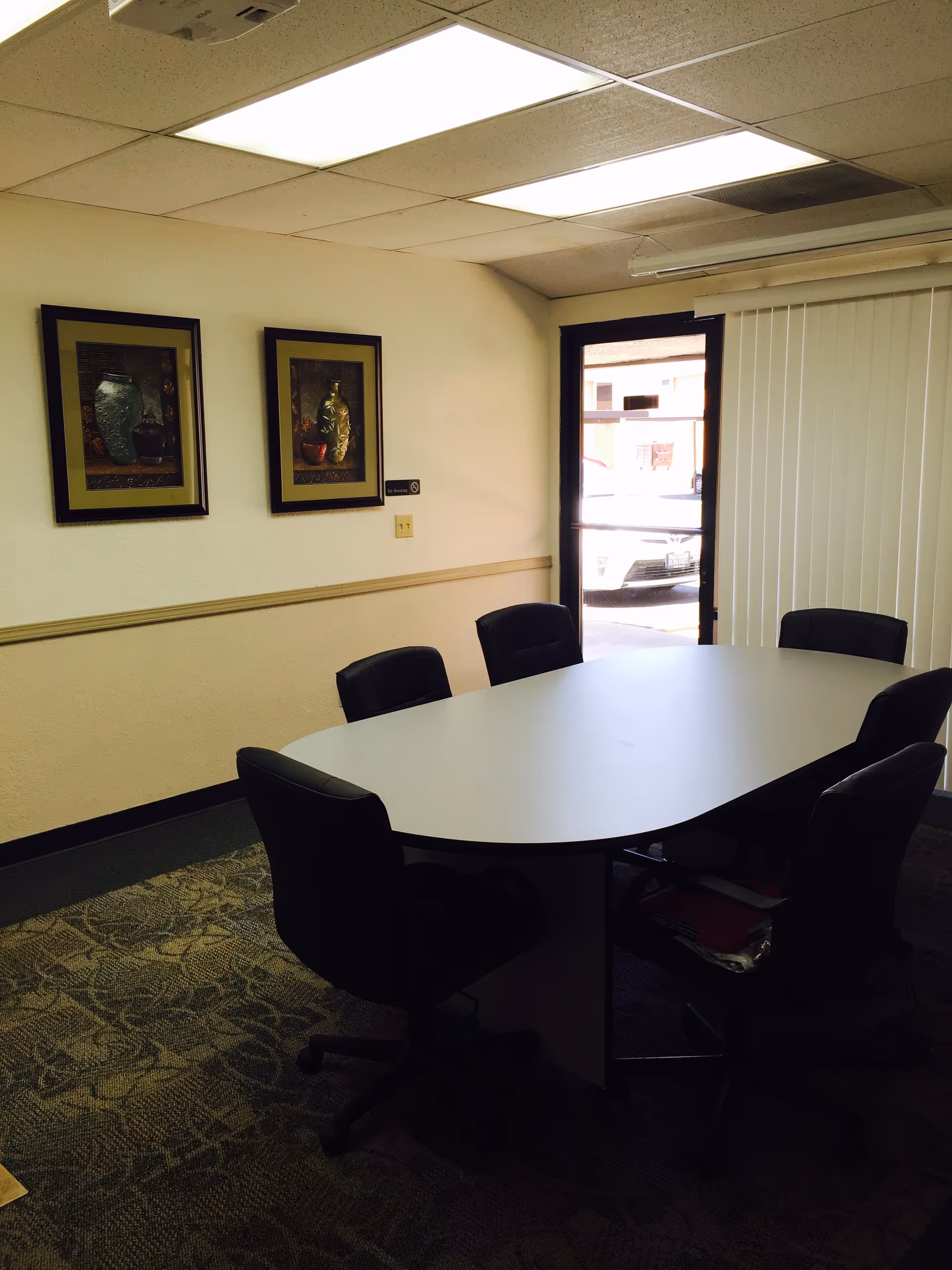 A small conference room with an oval white table and black office chairs.