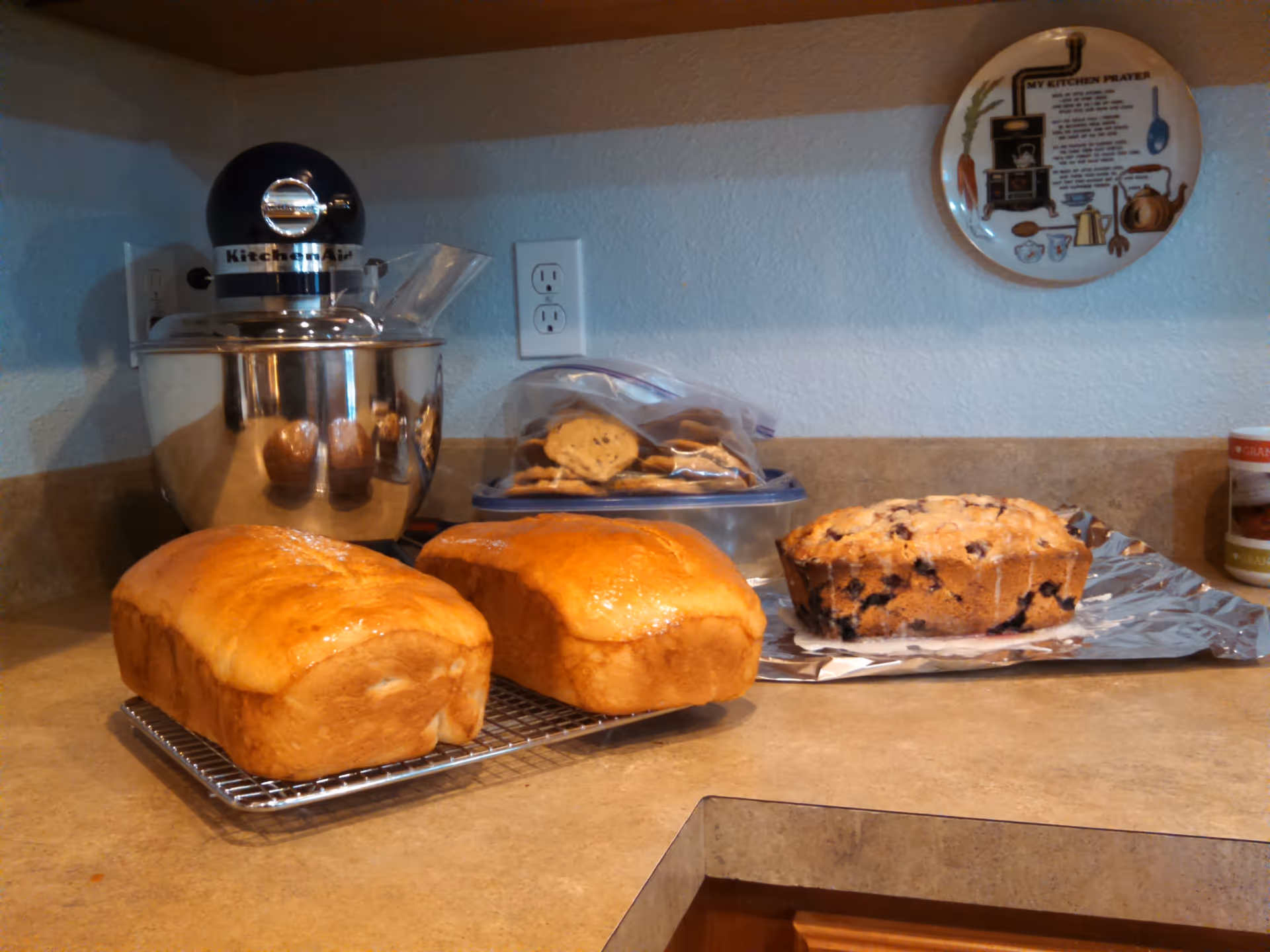 A kitchen counter with bread loaves, a mixer, and baking supplies.