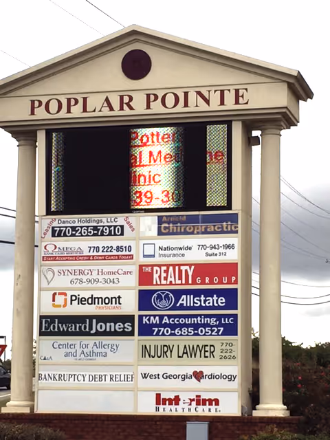 A tall outdoor signboard on a building front listing Synergy HomeCare and other businesses.