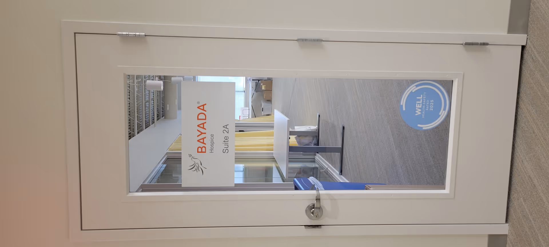 White door with BAYADA Hospice sign; interior reception area visible beyond glass panel.