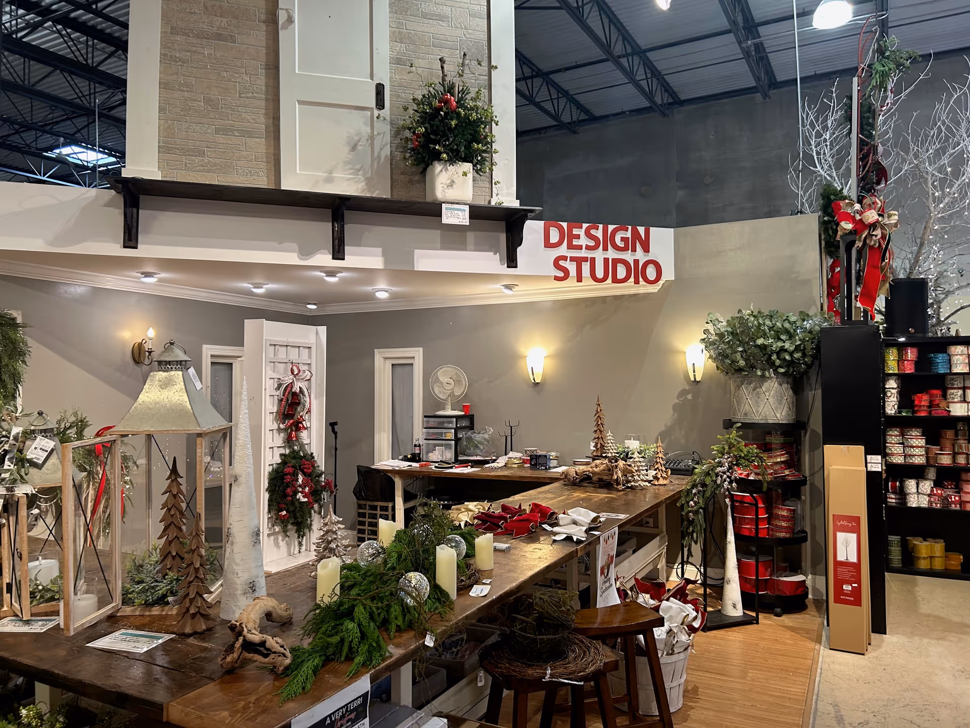 A busy interior design studio with holiday decorations and a long work table.