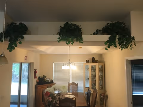 Interior dining area in a senior living facility with plants and a chandelier.