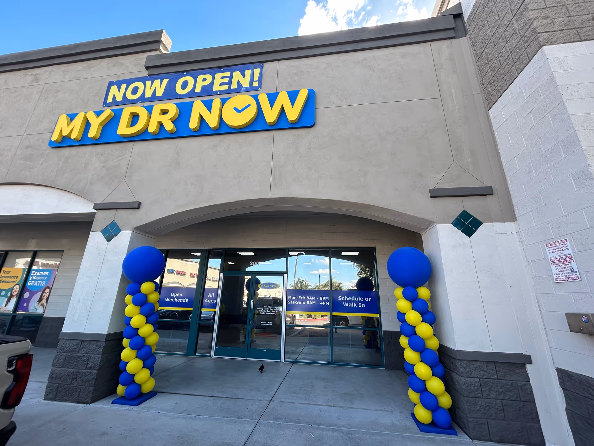 Front exterior of a building with blue and yellow MY DR NOW sign and balloons