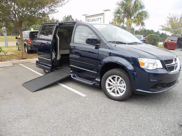 Blue wheelchair-accessible van with deployed ramp in parking lot near MobilityWorks sign.