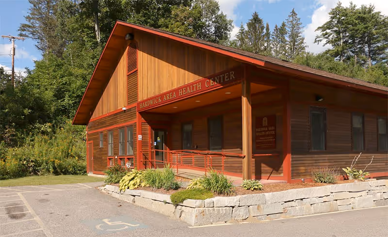 Wooden building labeled Hardwick Area Health Center with ramp and landscaped entrance.