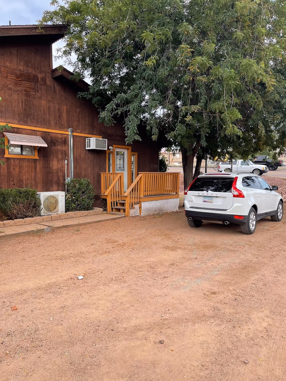 Exterior of a wooden building with a porch and a parked SUV.
