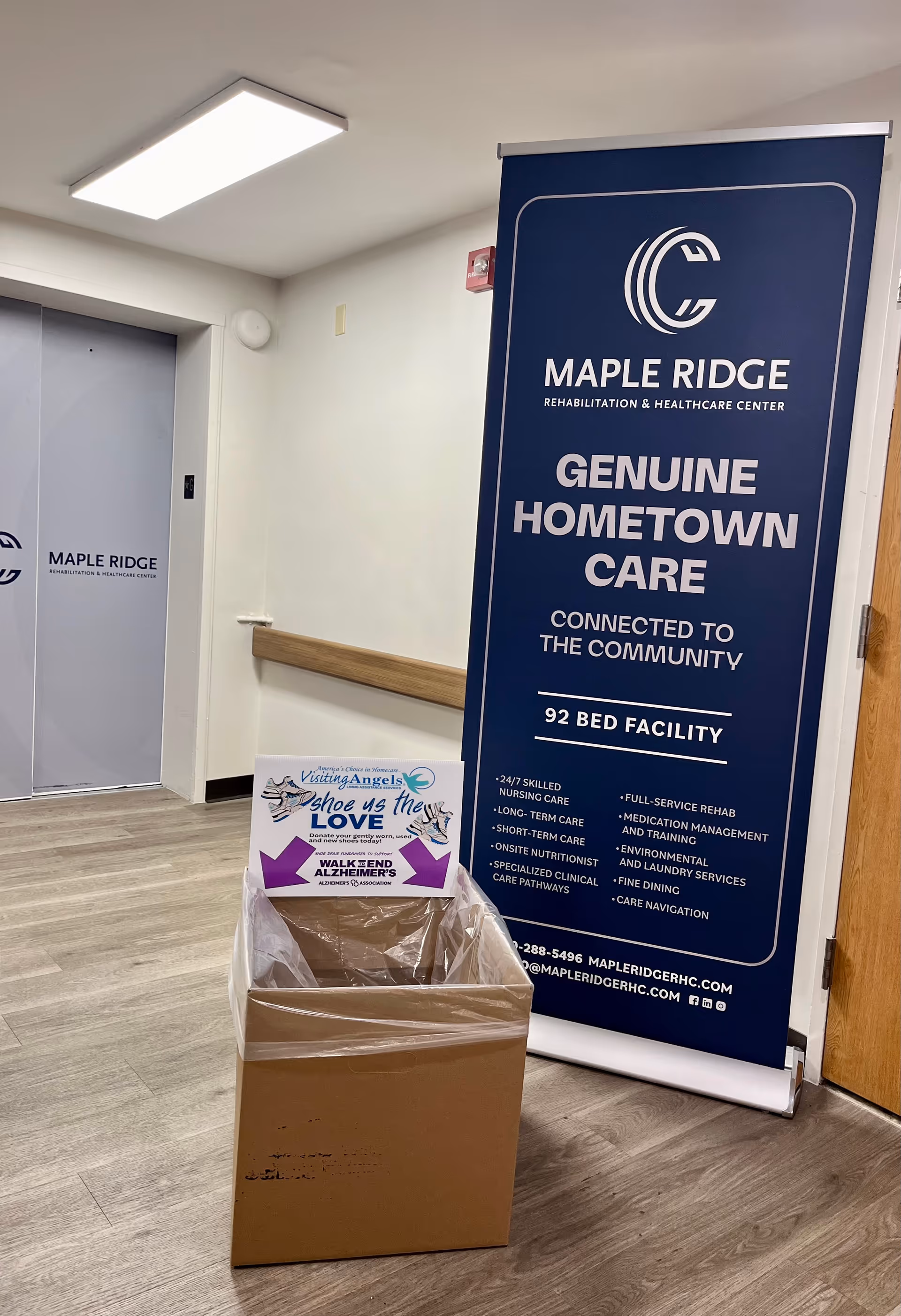 Interior facility hallway featuring a large blue Maple Ridge banner and a cardboard donation box.