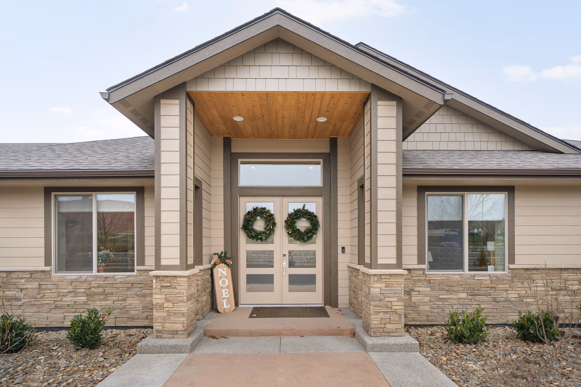 Front entrance of a modern senior living facility with wreaths and stone accents.