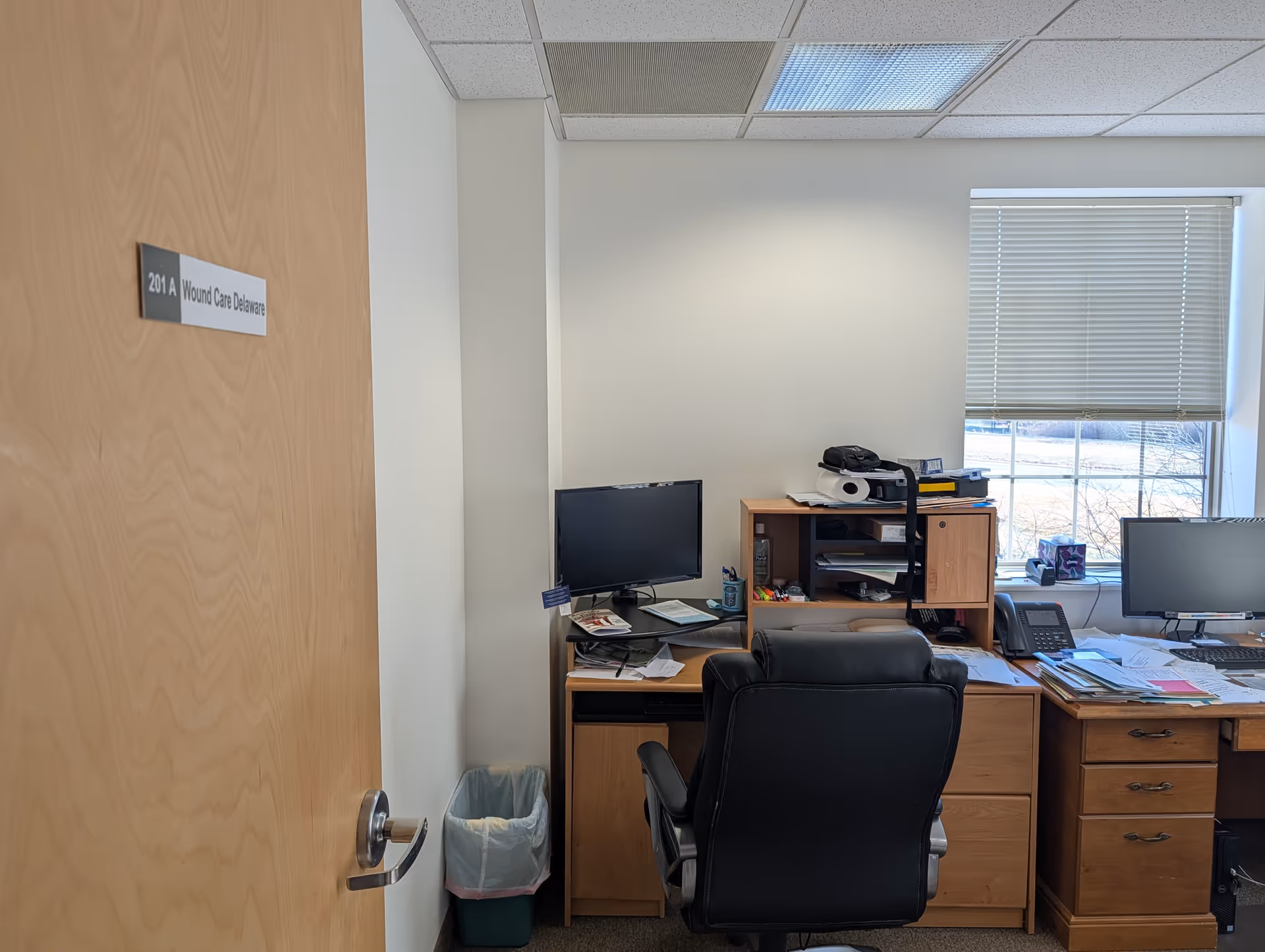 Office space with desk, computer, papers, and a door labeled Wound Care Delaware.