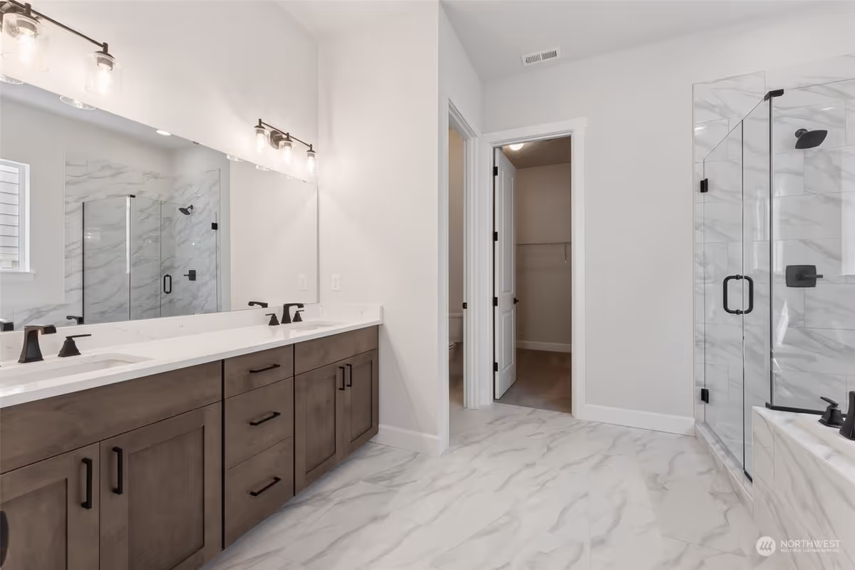 Modern bathroom with double vanity, marble floors, and a glass-enclosed shower.