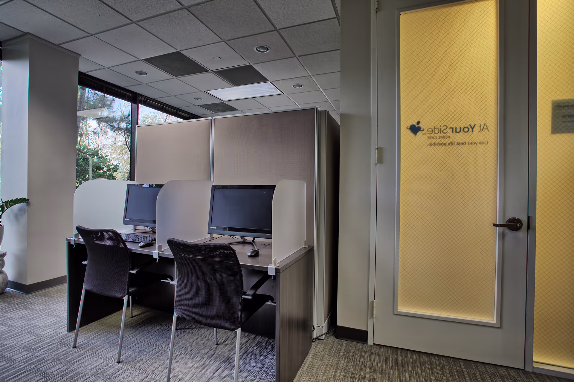 Interior office area with cubicles, computer desks, and a frosted yellow door.