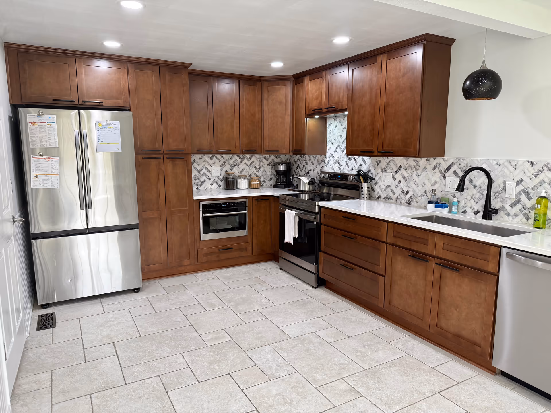 Modern kitchen with brown cabinets, stainless steel appliances, and a patterned backsplash.