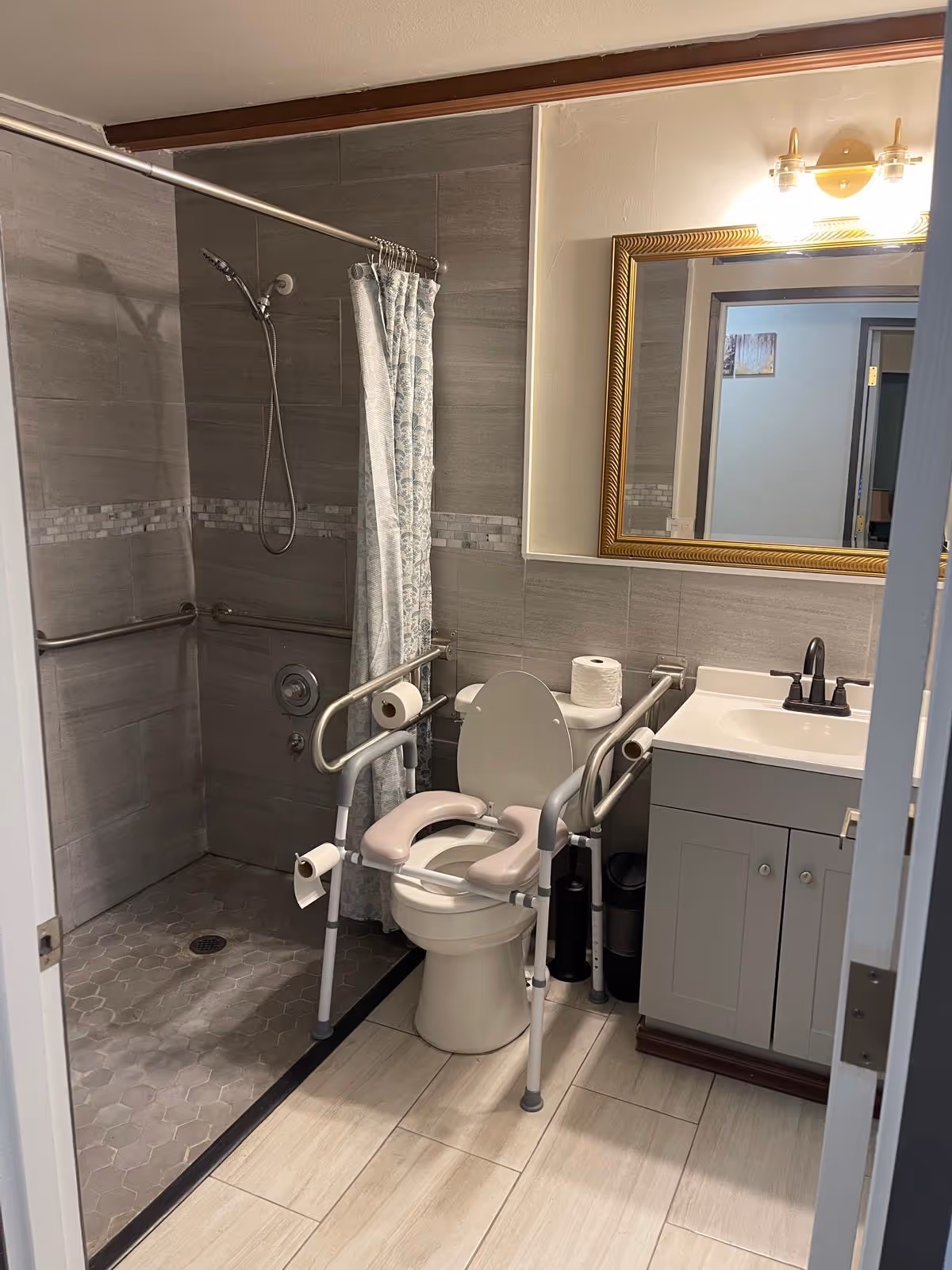 Accessible bathroom with shower, toilet, grab bars, and sink in a senior facility.