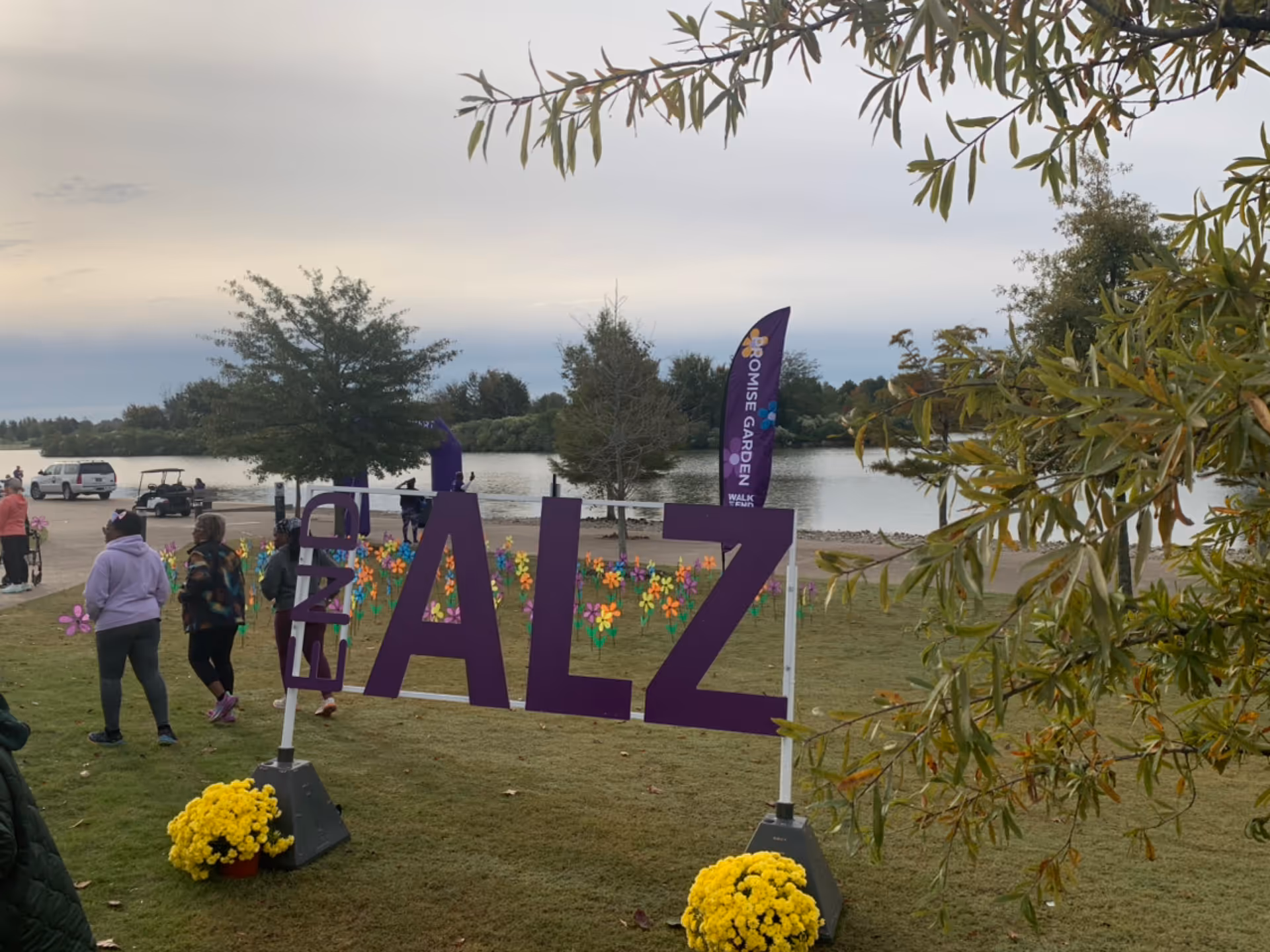 Lakeside outdoor Alzheimer's awareness event with oversized ALZ letters and participants.