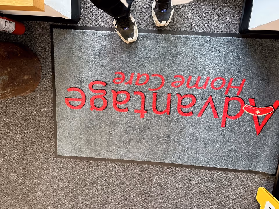 A person stands on a gray entry mat that reads Advantage Home Care.
