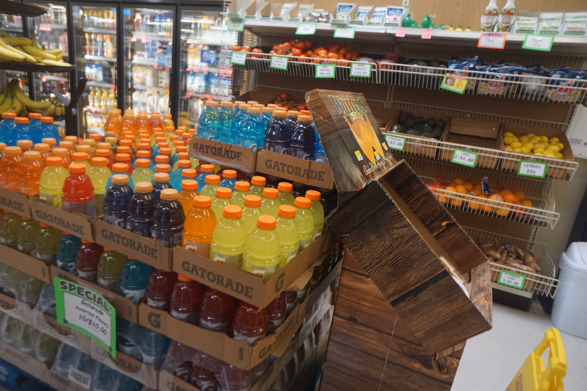 Colorful Gatorade bottles stacked on crates beside a fruit display in a store aisle.