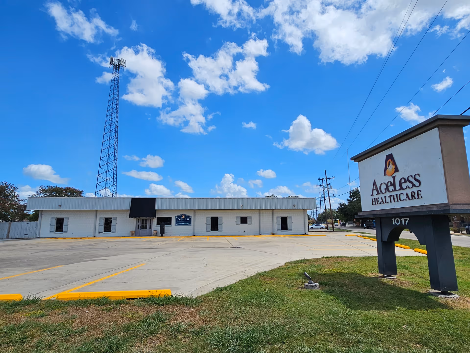 Exterior view of Ageless Healthcare facility with sign, parking lot, and clear blue sky.