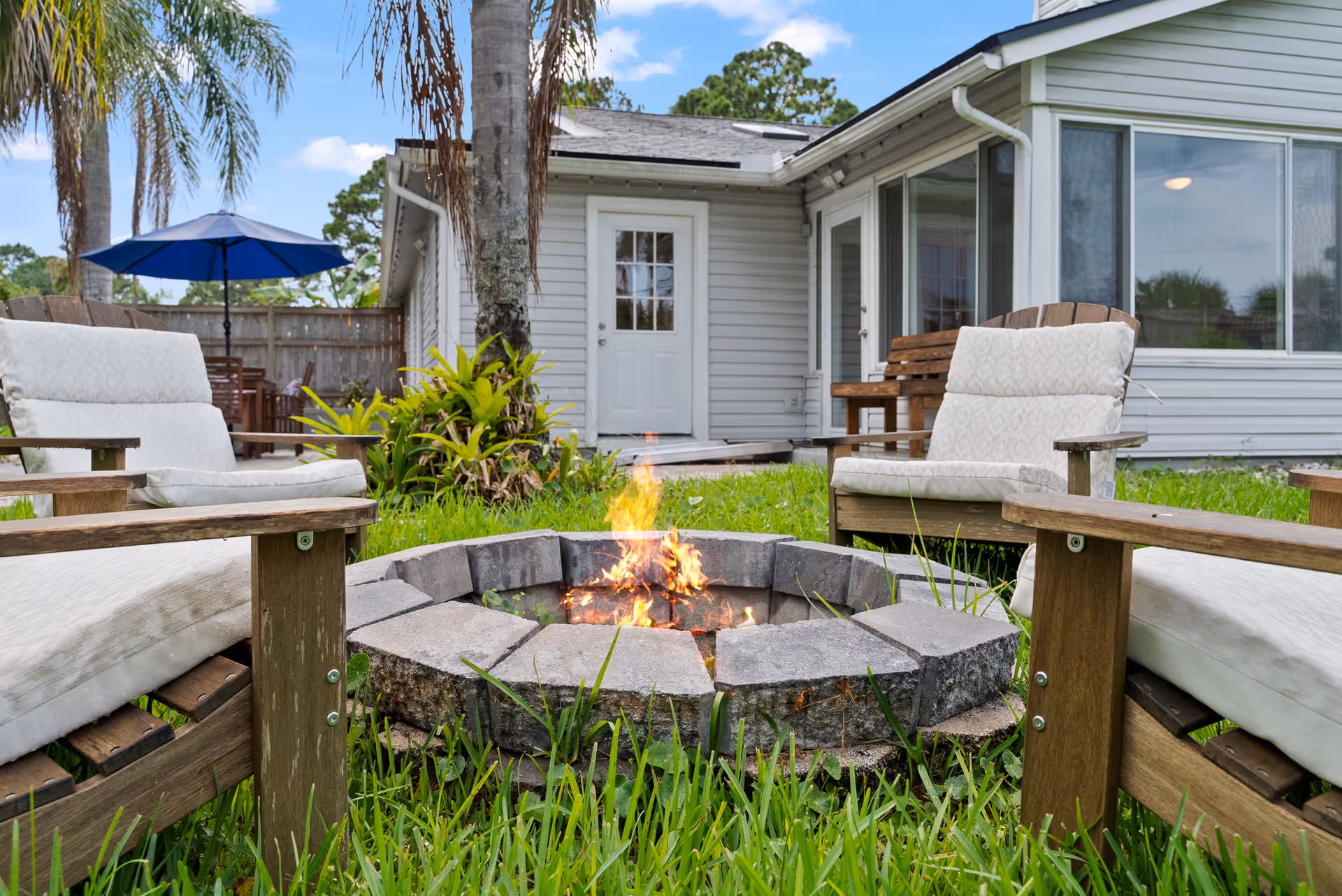 Backyard patio with fire pit seating and a house in the background.